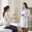 Woman Talking To Female Doctor Sitting on Examination Bed at Clinic